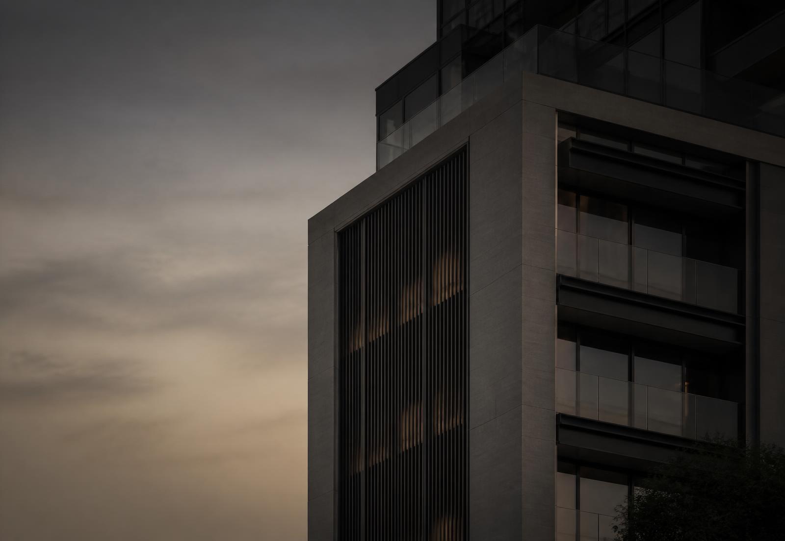 The corner of a contemporary stone and glass building at dusk
