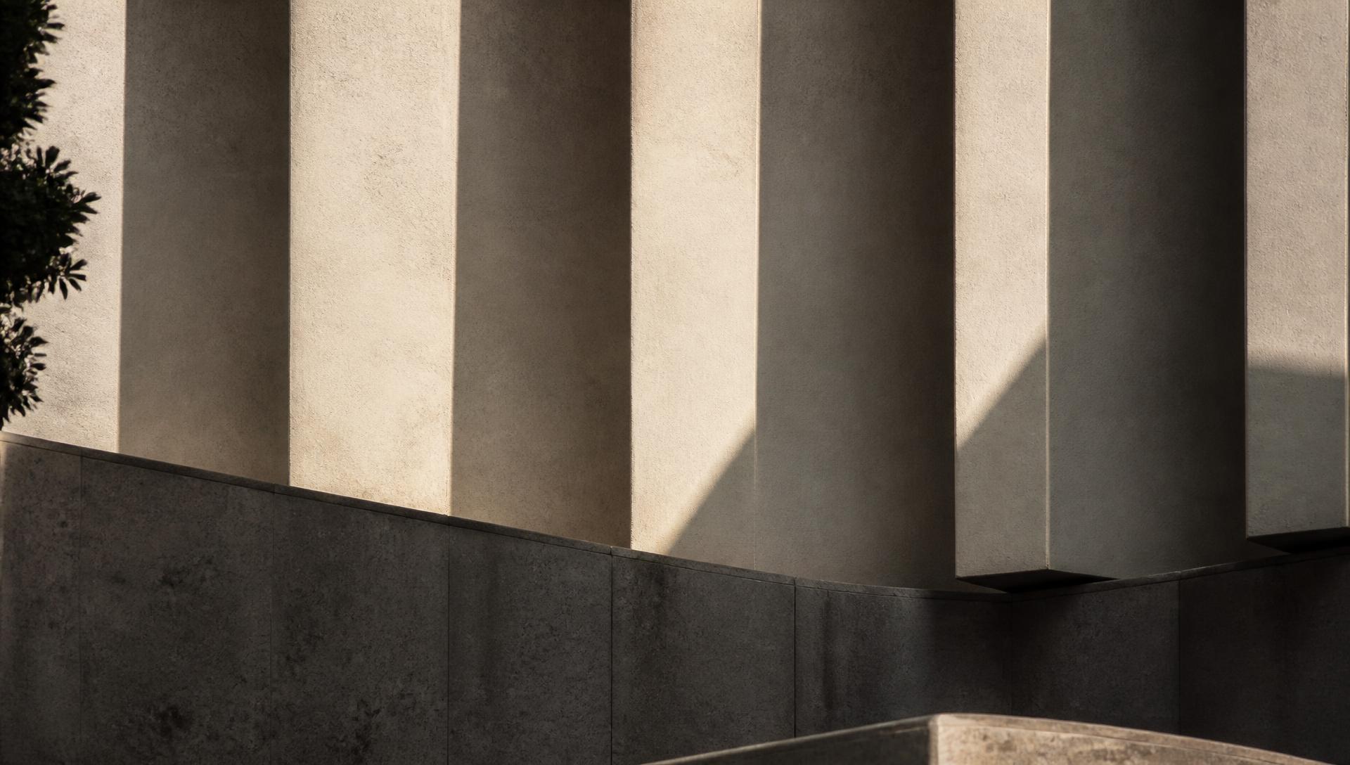 Raking daylight across the stone façade of a modern building